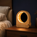 Lumidusk Dawn sunrise alarm clock with glowing amber moon lamp on a walnut nightstand in a navy bedroom
